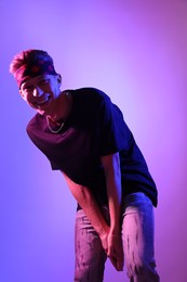 Stylish young man on color background in neon lights