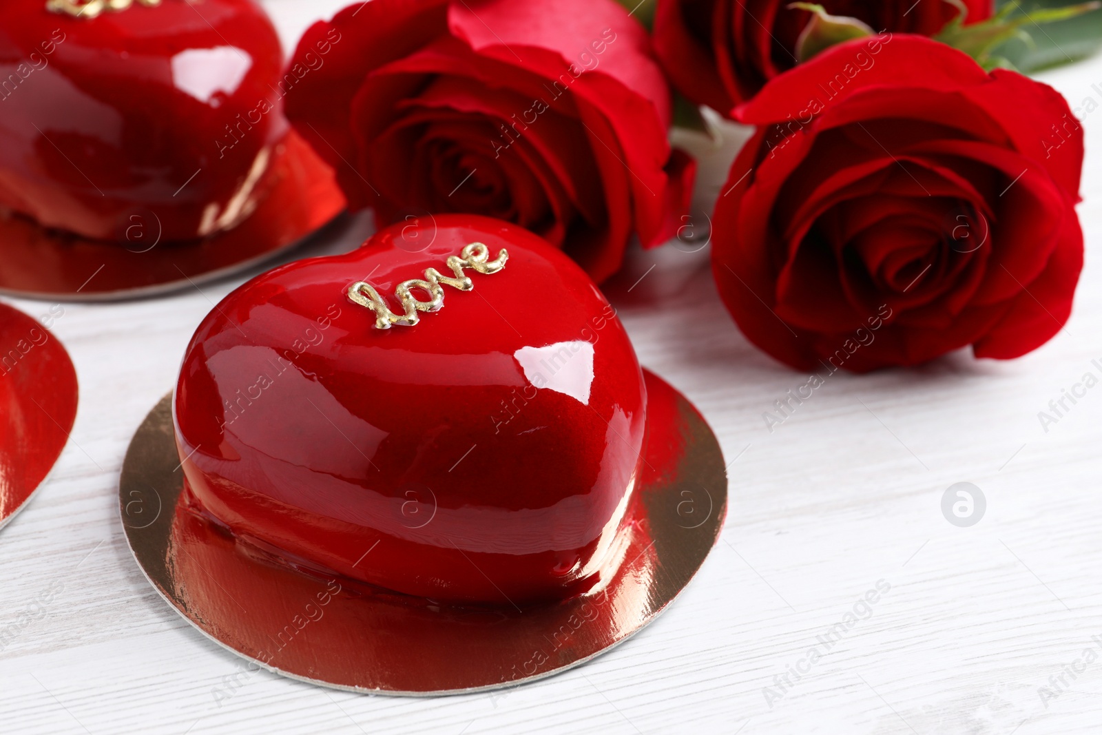 Photo of St. Valentine's Day. Delicious heart shaped cakes and roses on white wooden table, closeup