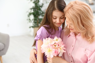 Photo of Little daughter congratulating her mature mom at home, space for text. Happy Mother's Day