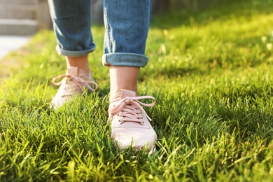 Photo of Woman in stylish sneakers on green grass, closeup