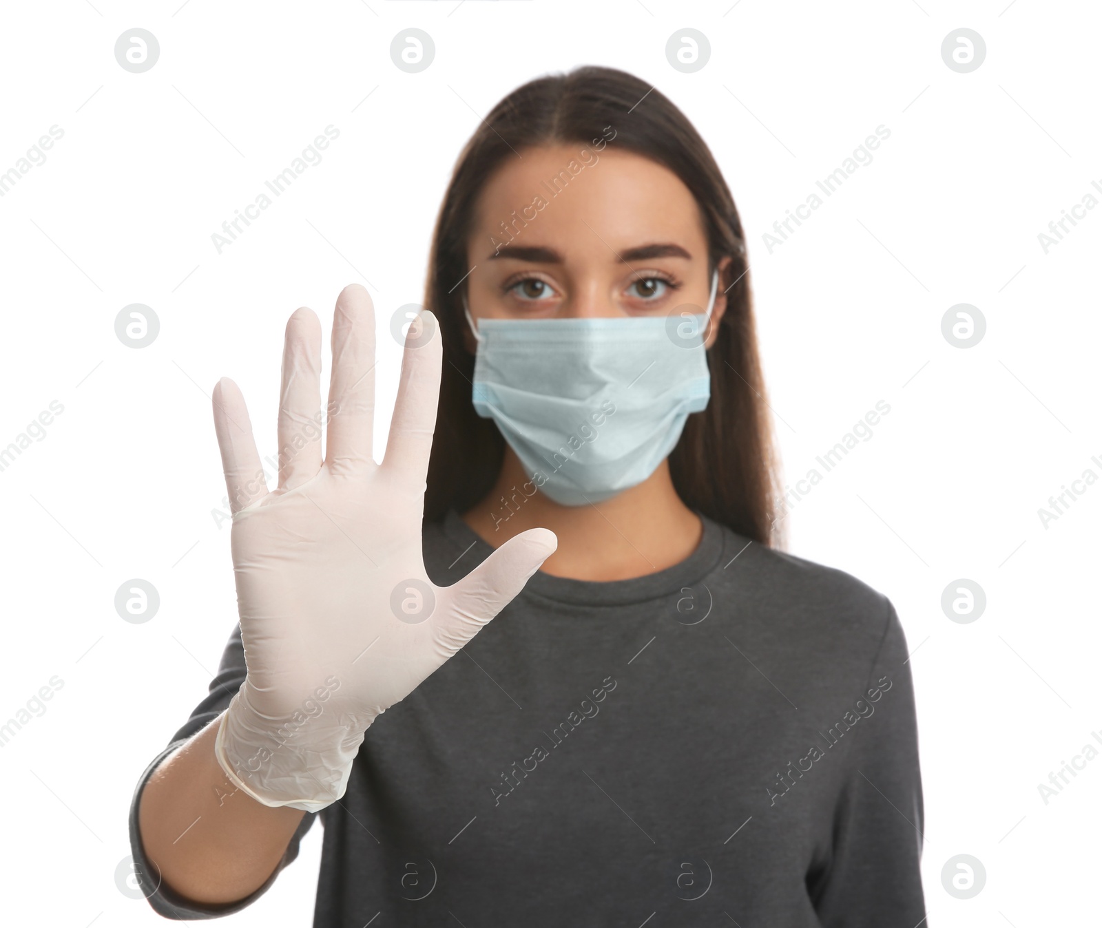 Photo of Woman in protective face mask and medical gloves showing stop gesture against white background, focus on hand