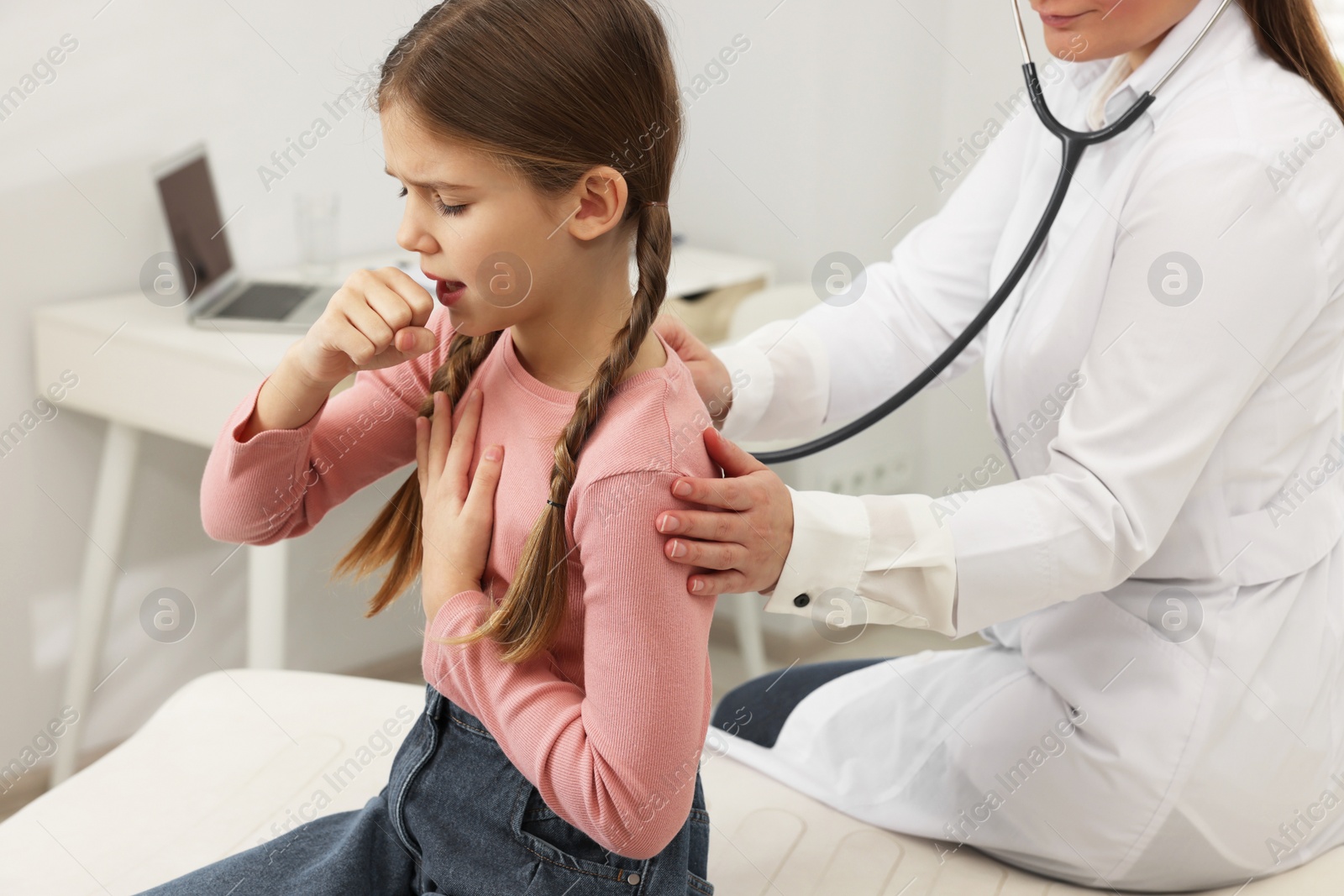 Photo of Doctor examining coughing girl in hospital. Cold symptoms