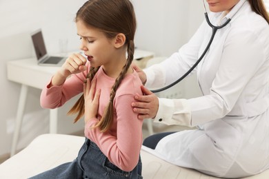 Photo of Doctor examining coughing girl in hospital. Cold symptoms