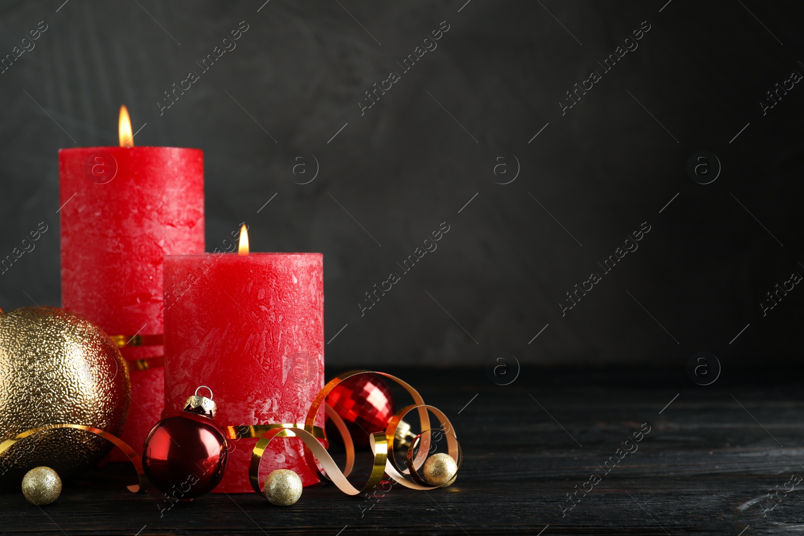 Photo of Beautiful Christmas composition with burning red candles on black wooden table. Space for text
