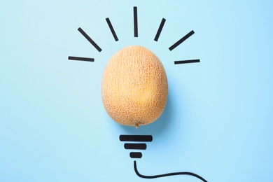 Composition with melon as lamp bulb on light blue background, top view