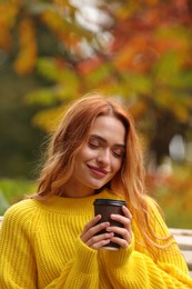 Portrait of beautiful woman with paper cup enjoying autumn outdoors