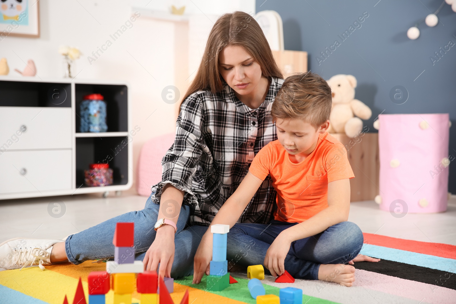 Photo of Young woman and little boy with autistic disorder playing at home