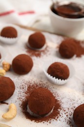 Delicious chocolate truffles powdered with cocoa on table, closeup