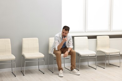 Photo of Man sitting on chair and waiting for appointment indoors