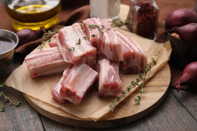 Photo of Cut raw pork ribs with thyme on wooden table