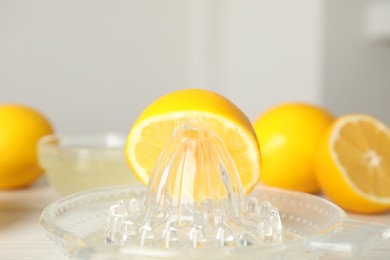 Photo of Plastic juicer with half of lemon on table, closeup