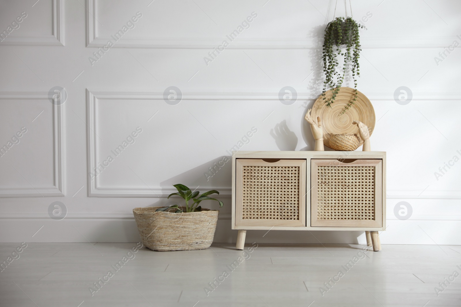 Photo of Wooden commode near white wall in room. Interior design