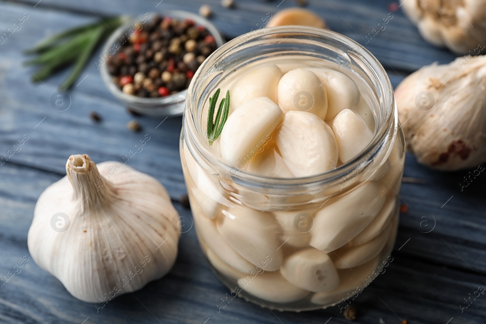 Photo of Preserved garlic in glass jar on wooden table, closeup