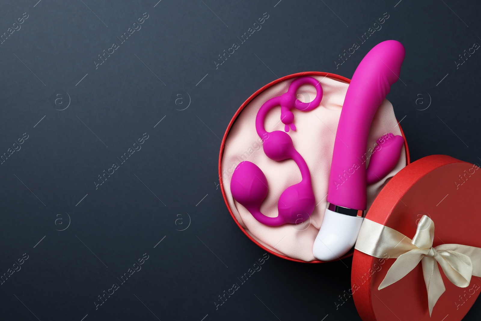 Photo of Pink sex toys in gift box on dark blue background, top view. Space for text