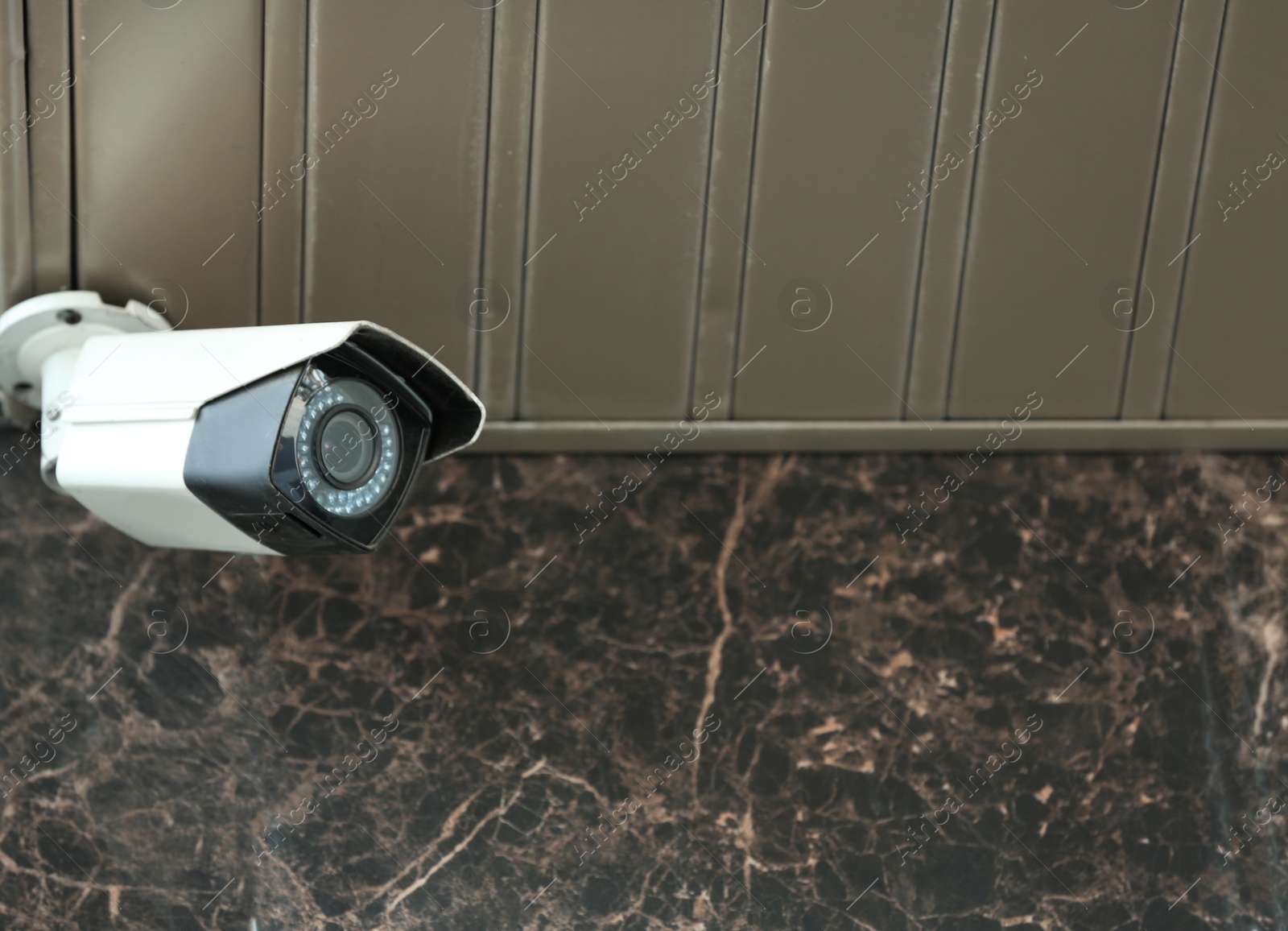 Photo of Modern CCTV security camera on building wall outdoors. Space for text