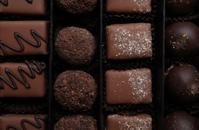 Photo of Different delicious chocolate candies in box, top view