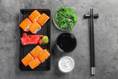 Flat lay composition with sushi rolls on grey table. Food delivery