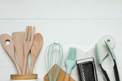 Set of different kitchen utensils on white wooden table, flat lay. Space for text