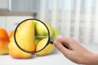 Image of Woman with magnifying glass exploring fruits, closeup. Poison detection
