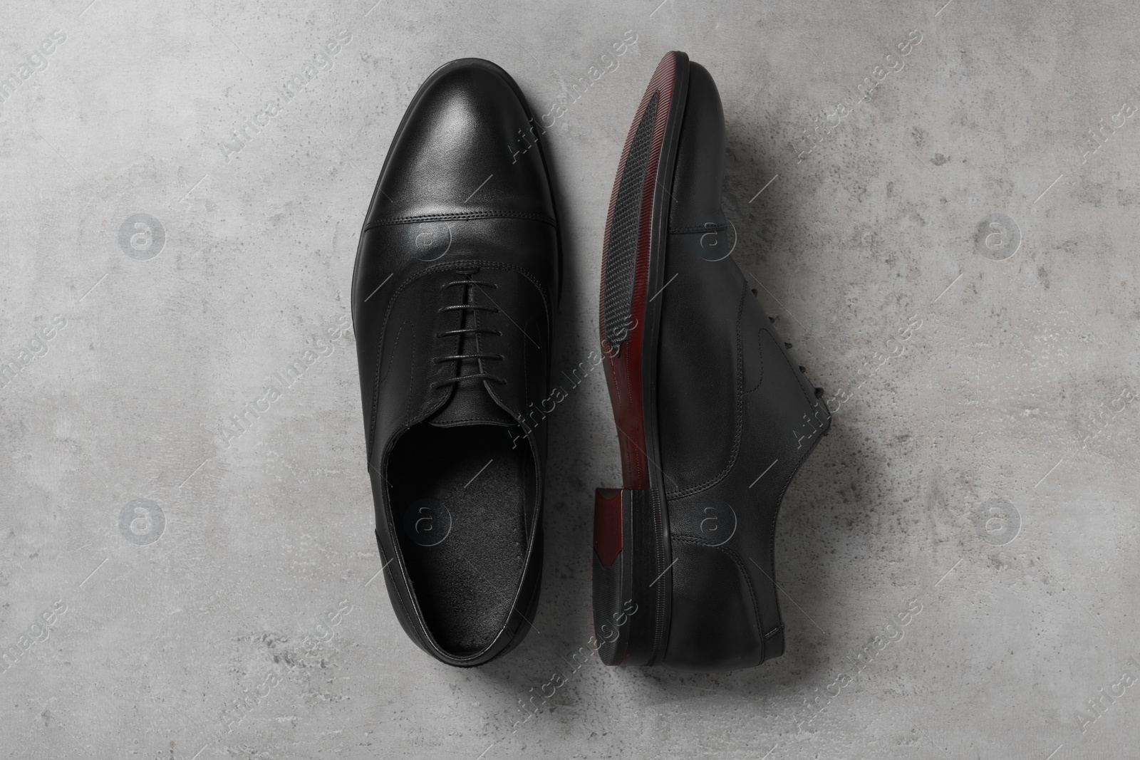 Photo of Pair of black leather men shoes on light grey surface, top view