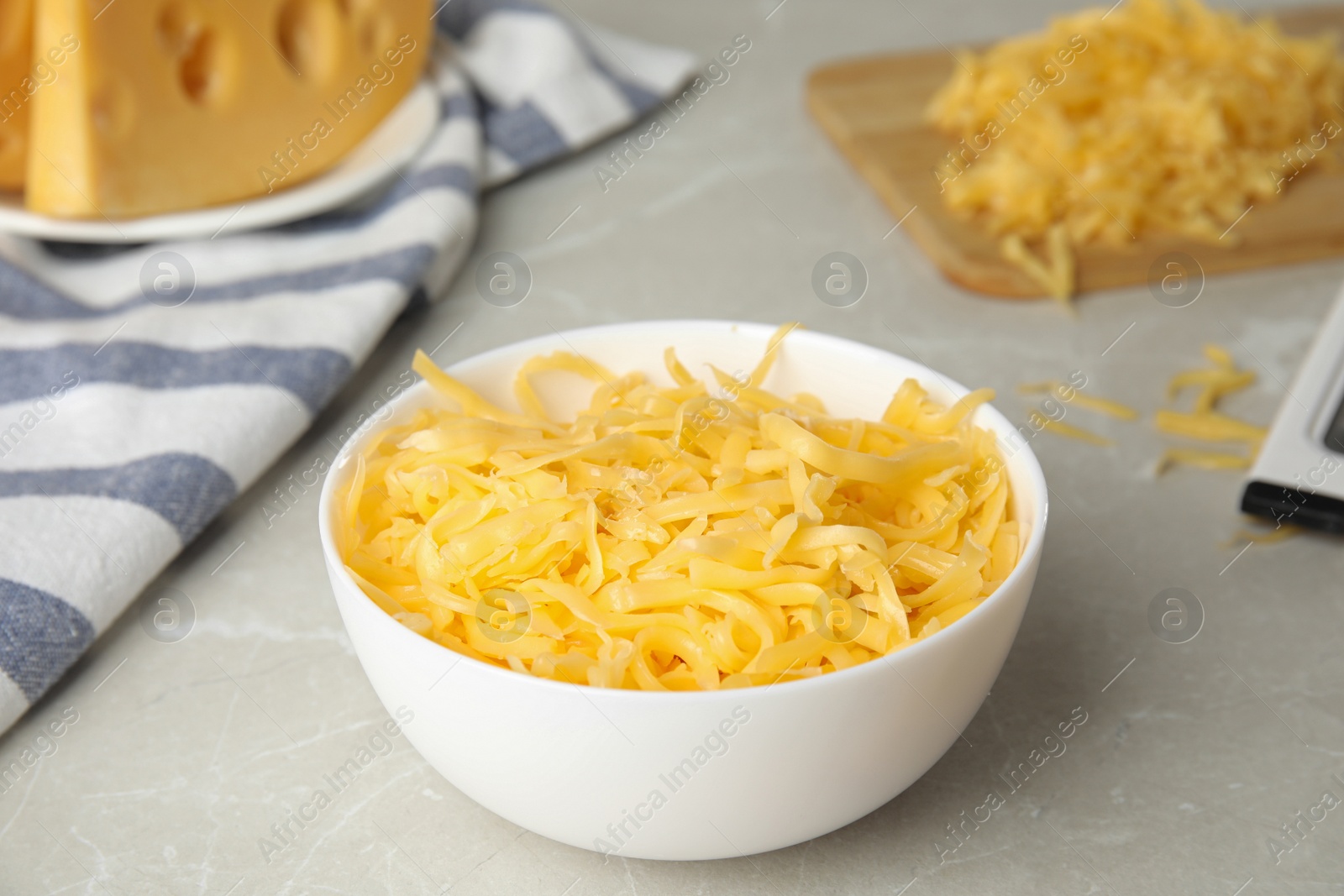 Photo of Delicious grated cheese in bowl on grey table