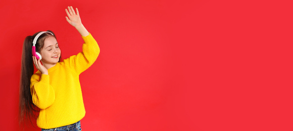 Image of Little girl listening to music with headphones on red background, space for text. Banner design