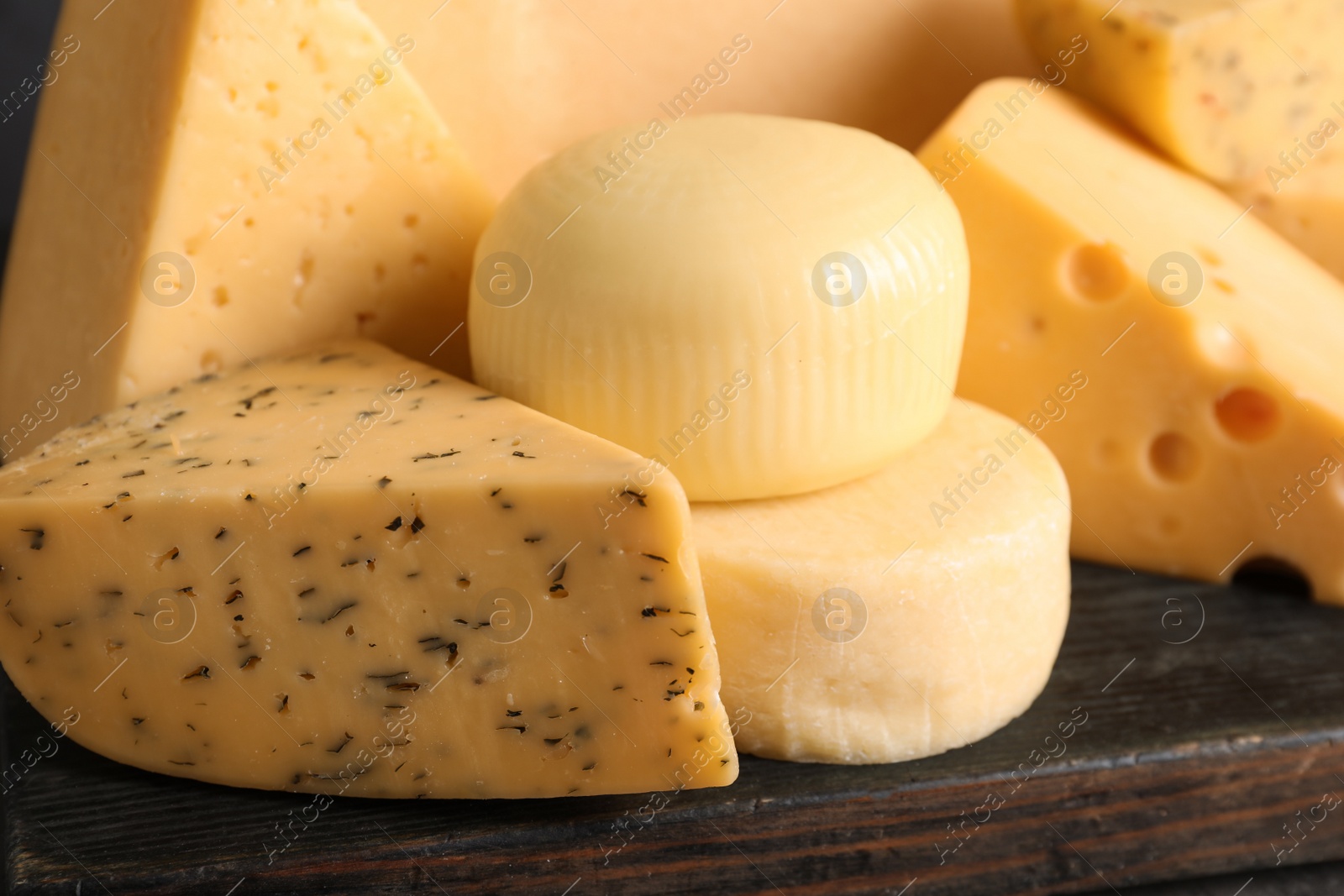 Photo of Wooden board with different sorts of cheese, closeup