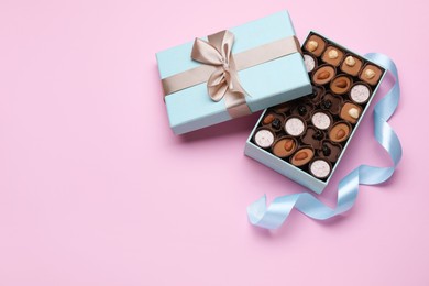 Photo of Open box of delicious chocolate candies on pink background, flat lay. Space for text