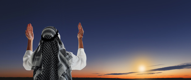 Muslim man praying outdoors at sunset. Banner design