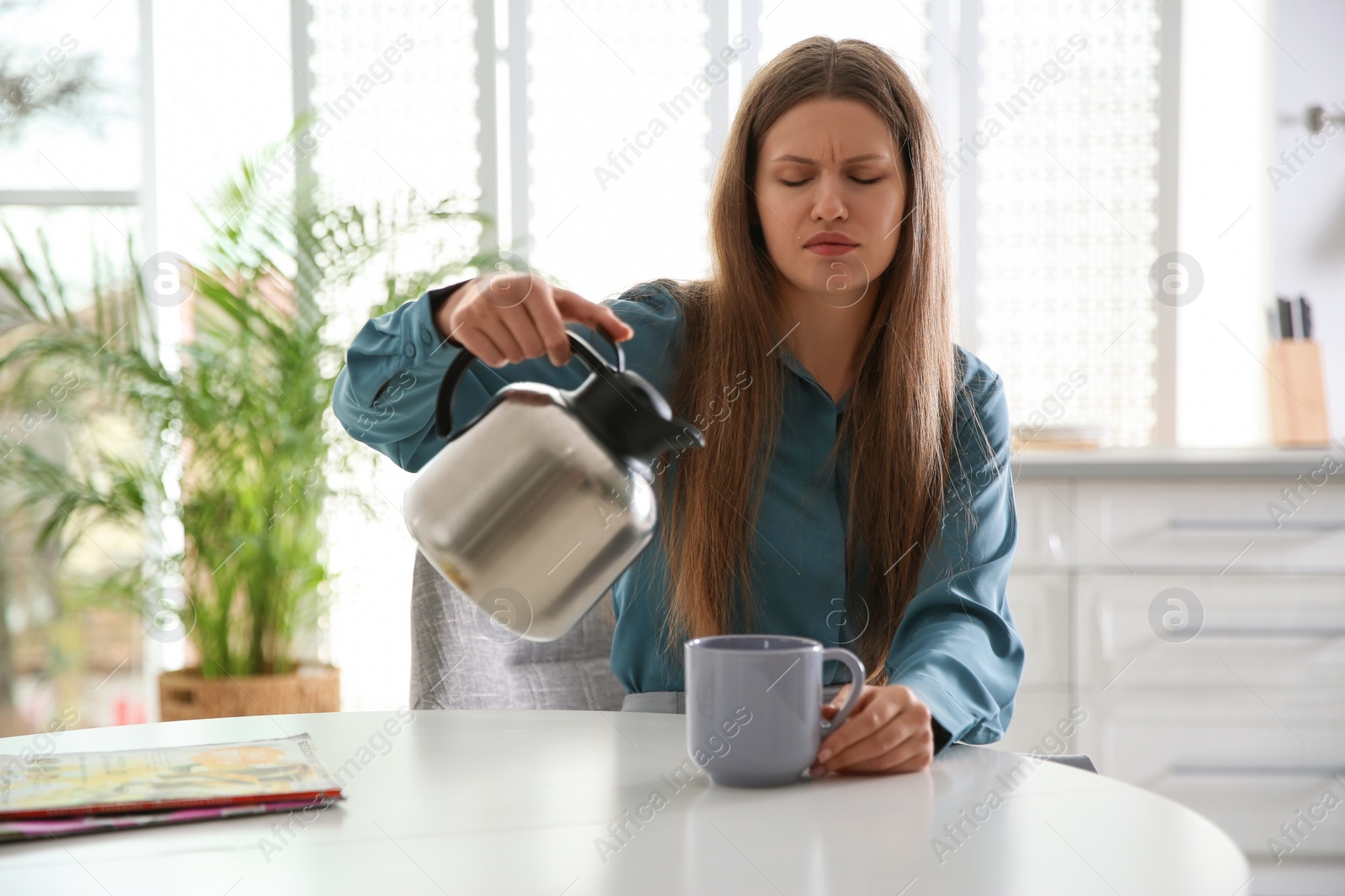 Photo of Sleepy young woman pouring coffee into cup at home in morning