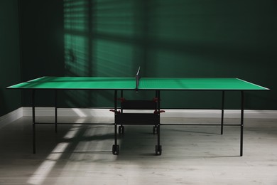 Photo of Green ping pong table with net in room