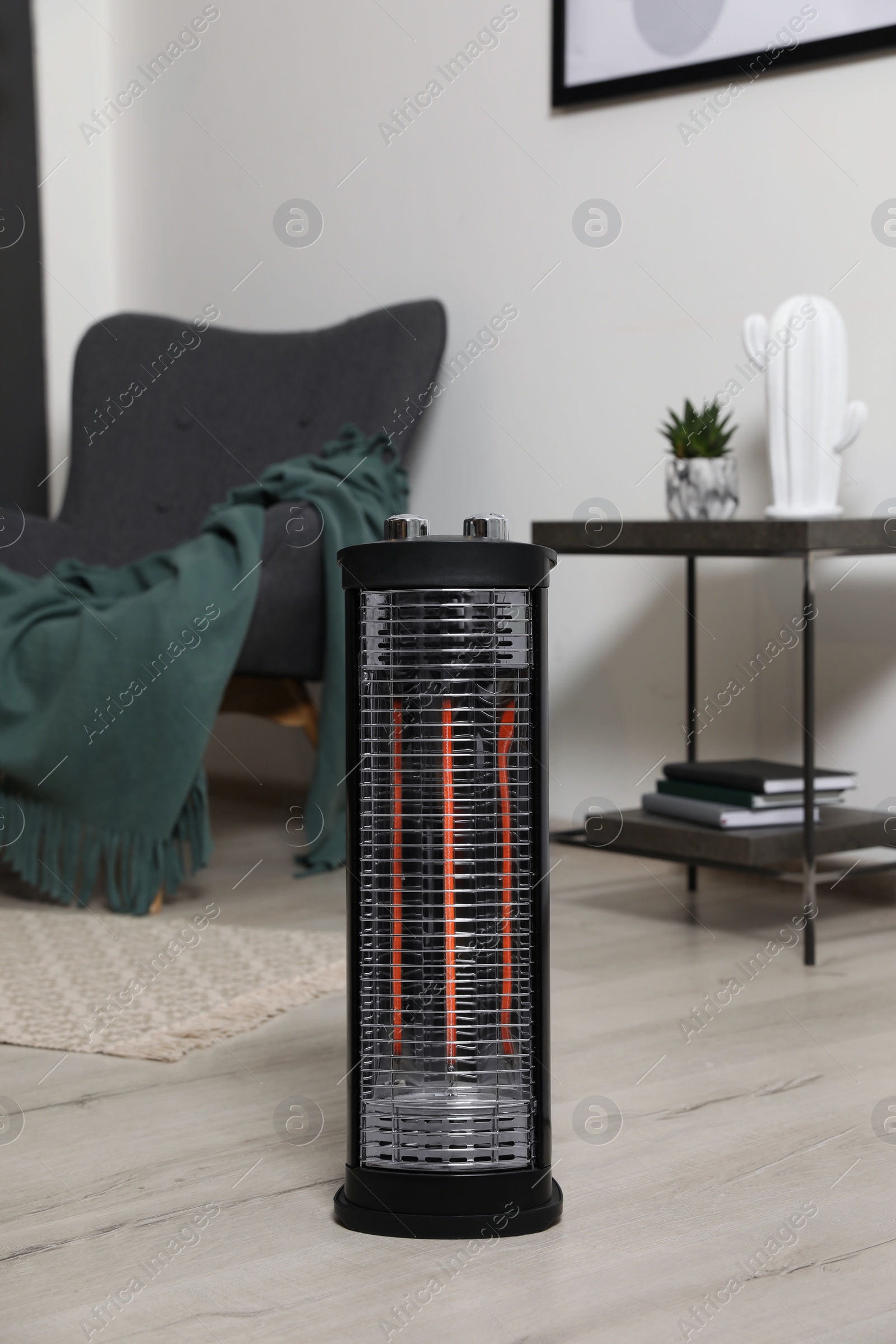 Photo of Modern electric halogen heater on floor in room interior