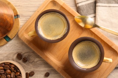 Delicious biscuit cups with espresso, spoon and coffee beans on wooden table, flat lay