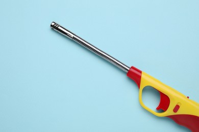 Photo of One gas lighter on light blue background, top view. Space for text