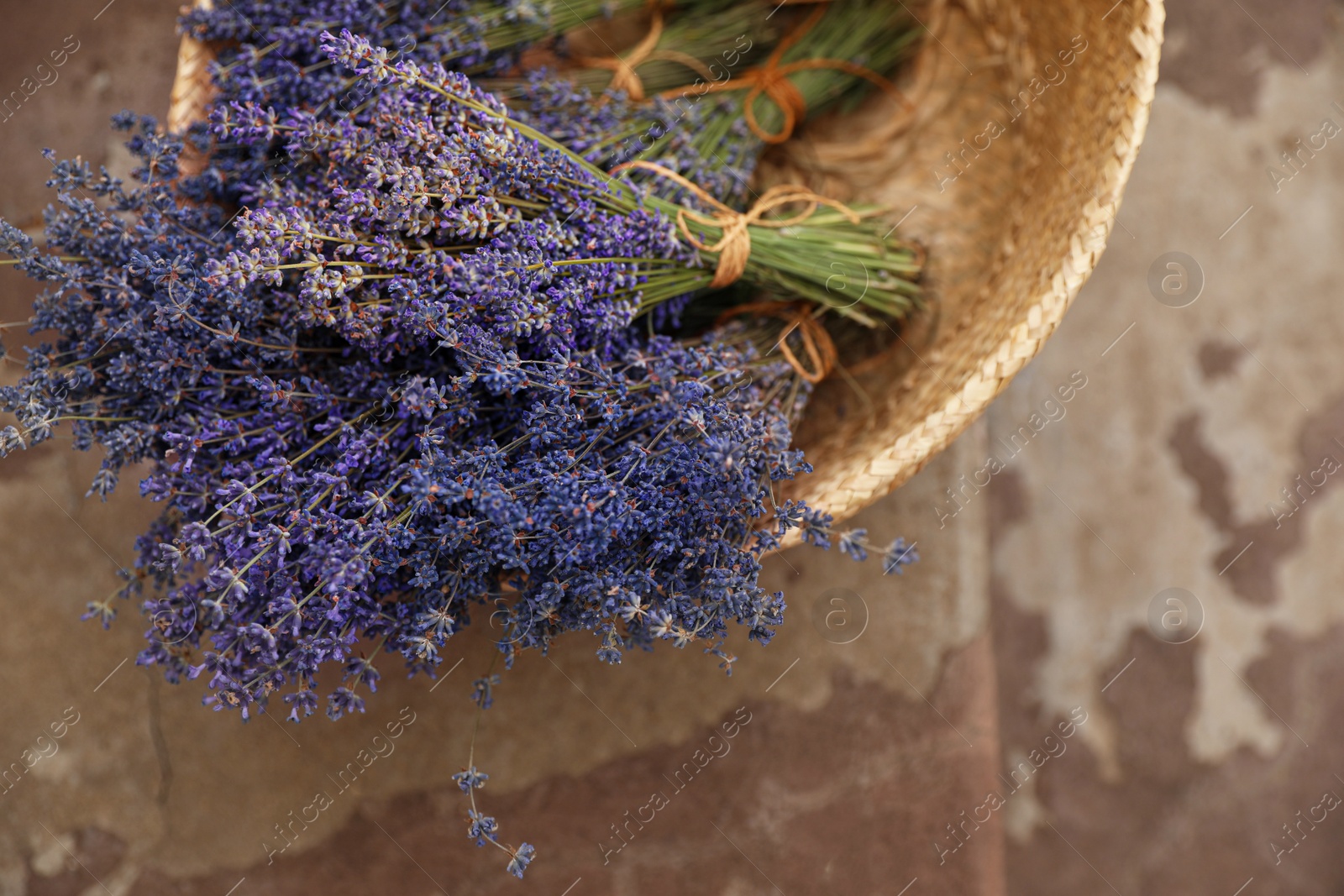 Photo of Wicker basket with lavender flowers on cement floor outdoors, top view
