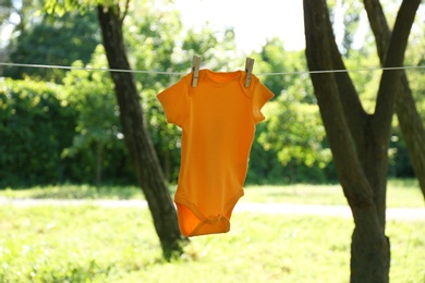 Photo of Color baby onesie hanging on clothes line outside