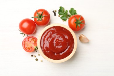 Photo of Delicious ketchup in bowl, peppercorns and tomatoes on white wooden table, flat lay