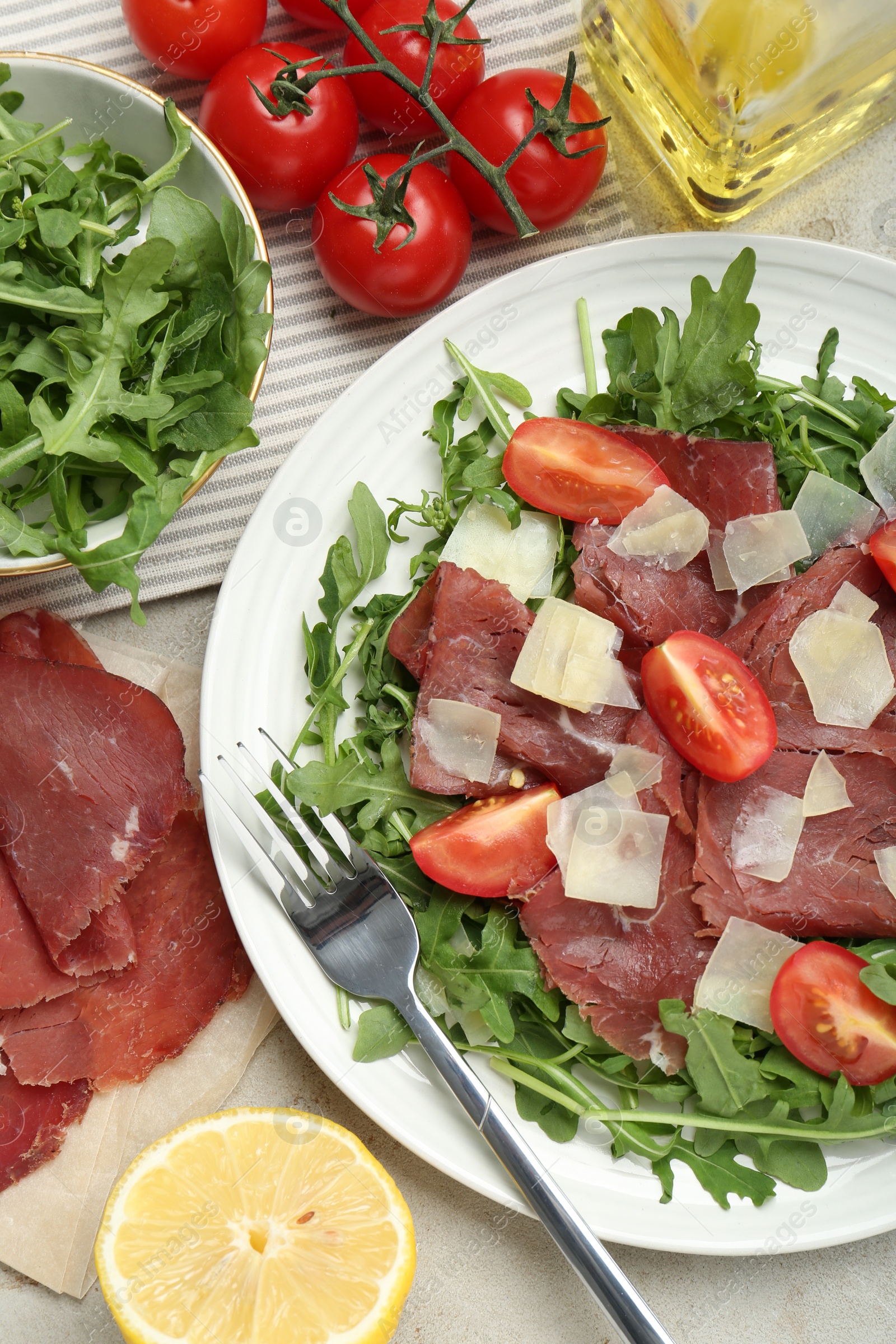 Photo of Flat lay composition with delicious bresaola salad on light grey table