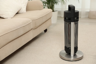 Photo of Modern electric halogen heater on floor in living room interior