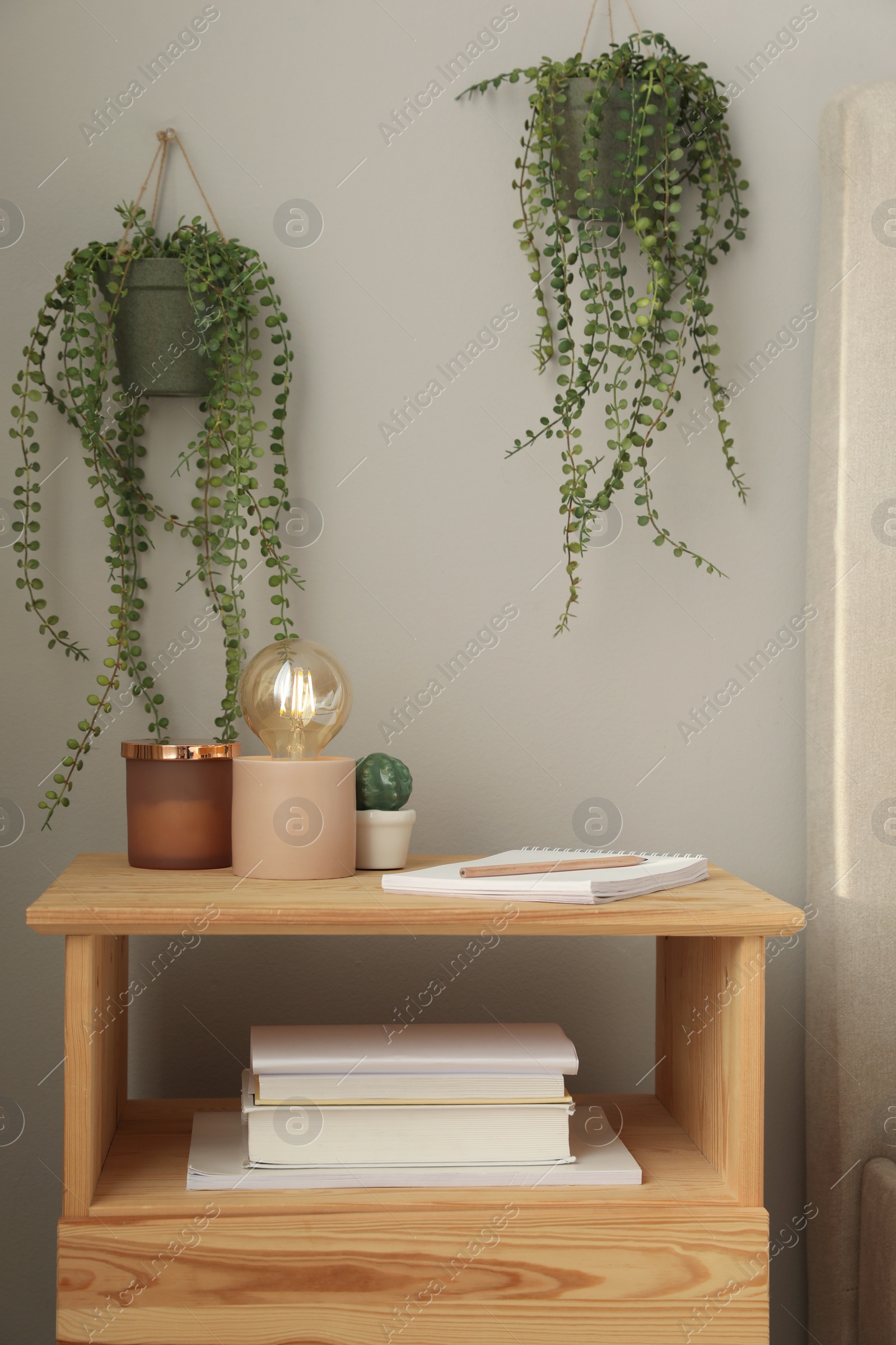 Photo of Stylish lamp and decor on wooden nightstand in room