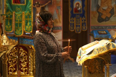 Photo of Mature woman holding burning candle in church