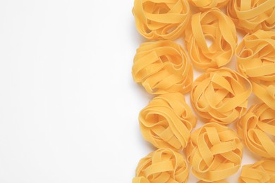 Raw tagliatelle pasta on white background, top view. Space for text