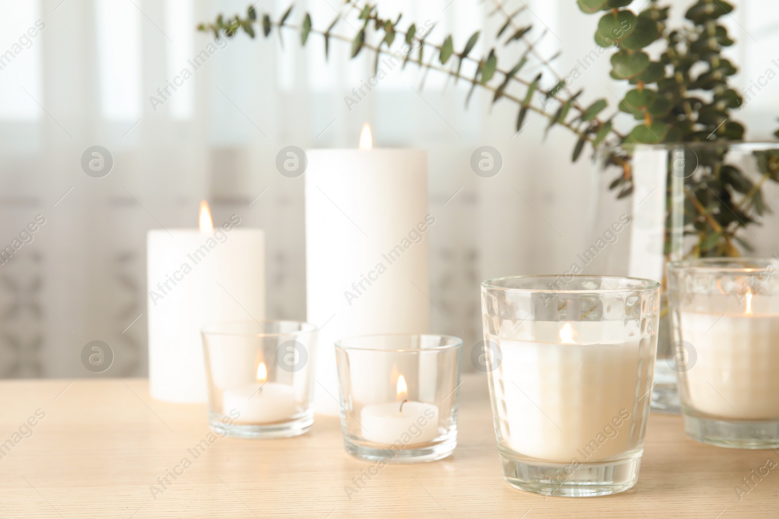 Photo of Burning aromatic candles on wooden table. Space for text