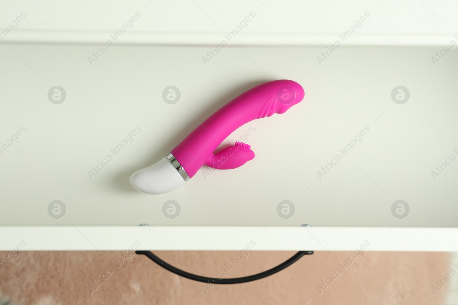 Photo of Modern vibrator in open white drawer, top view. Sex toys