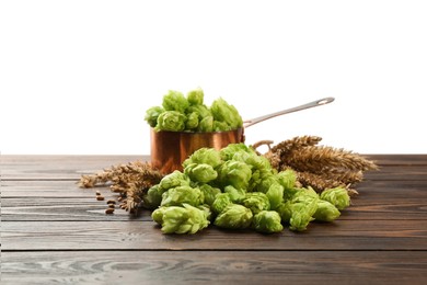 Fresh hop flowers and wheat ears on wooden table against white background