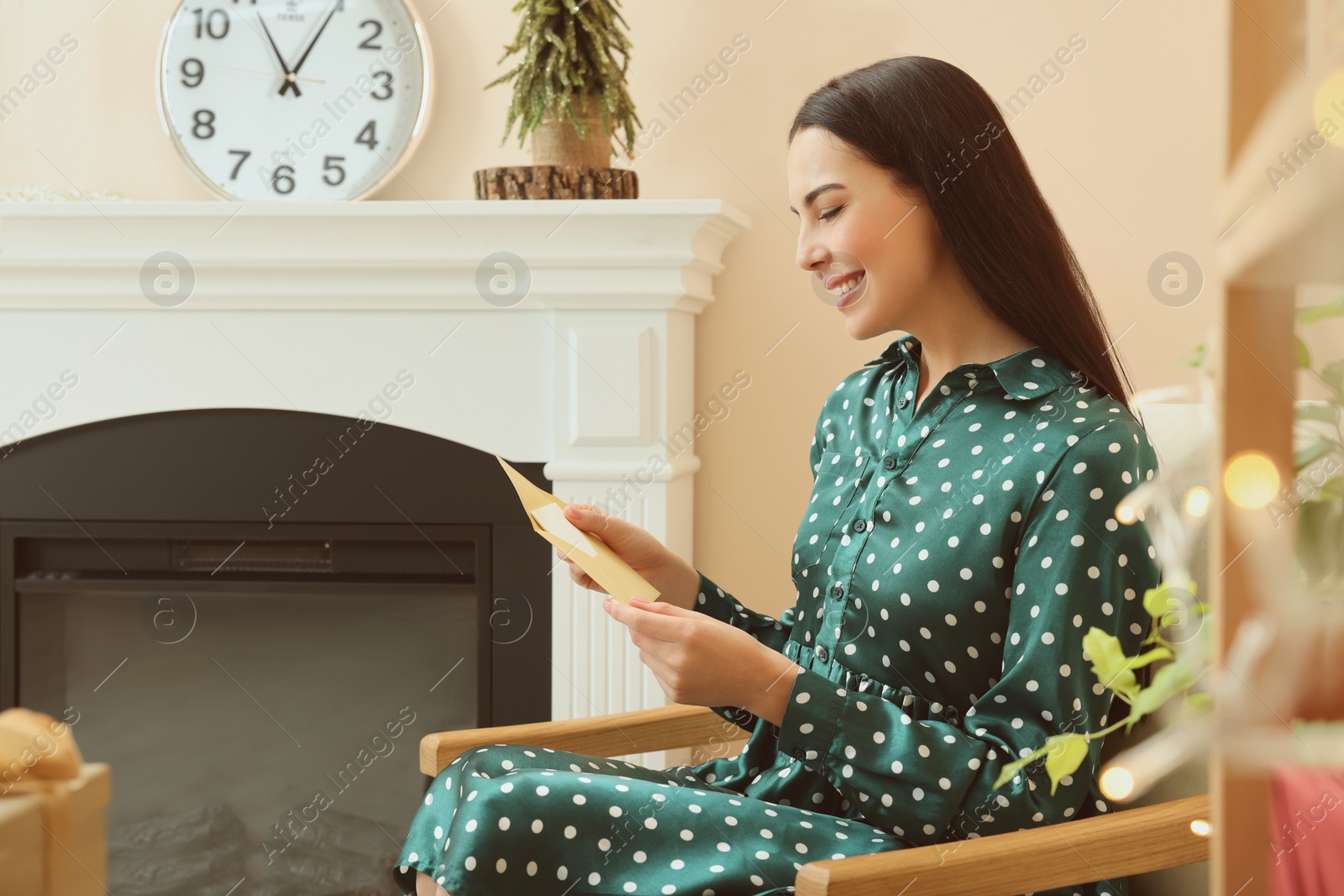 Photo of Happy woman reading Christmas greeting card in living room