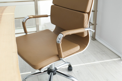 Photo of Comfortable workplace with office chair and wooden table, closeup