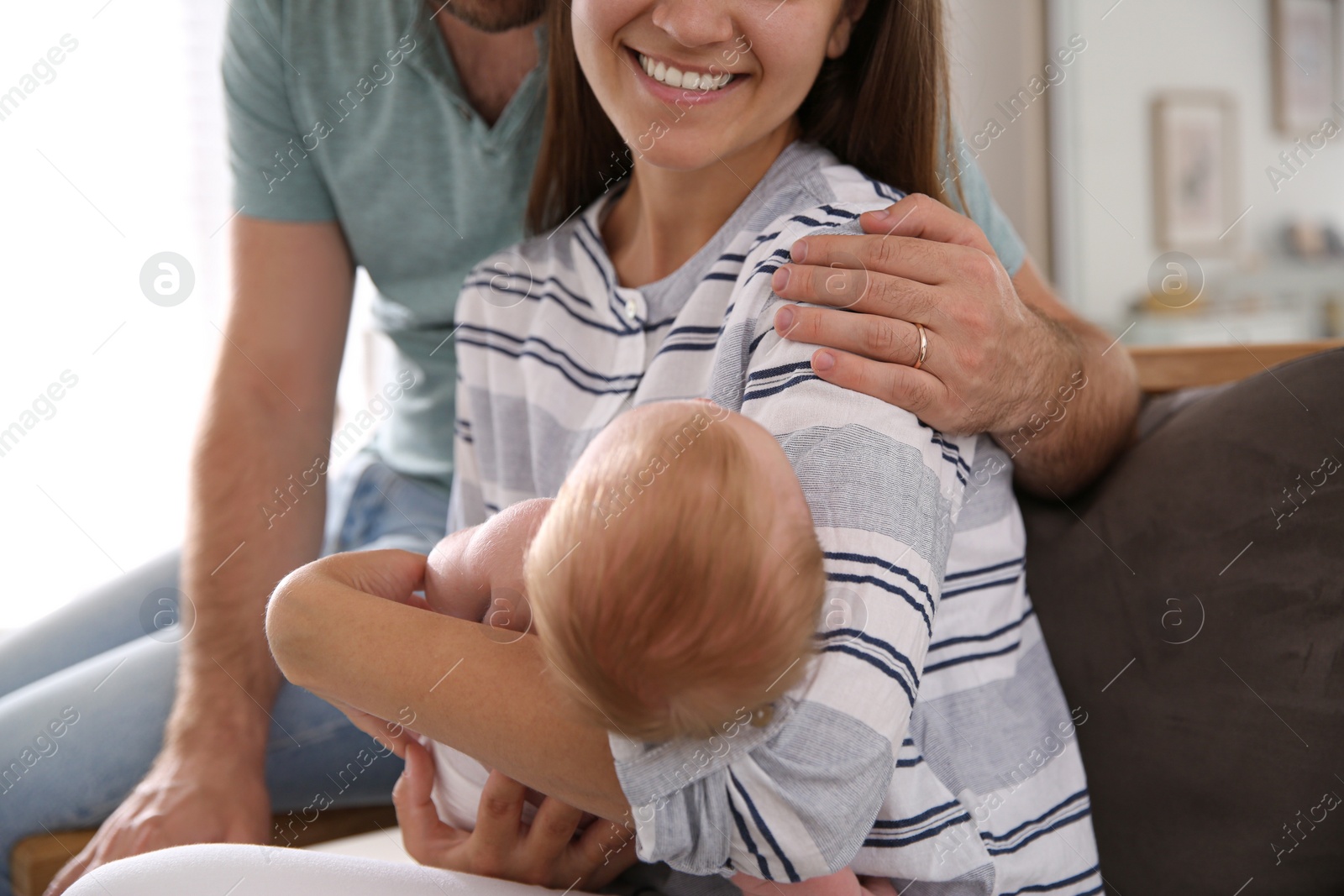 Photo of Happy couple with their newborn baby at home, closeup