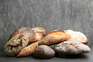 Different kinds of fresh bread on grey table