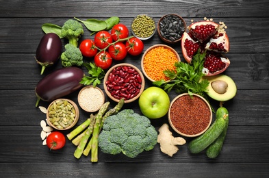 Different vegetables, seeds and fruits on black wooden table, flat lay. Healthy diet